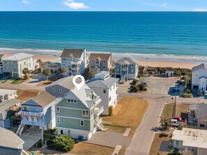 A coastal residential area with houses, a beach, and a clear view of the ocean. - Shore Sounds Fun by Topsail Realty (Holly Ridge)
