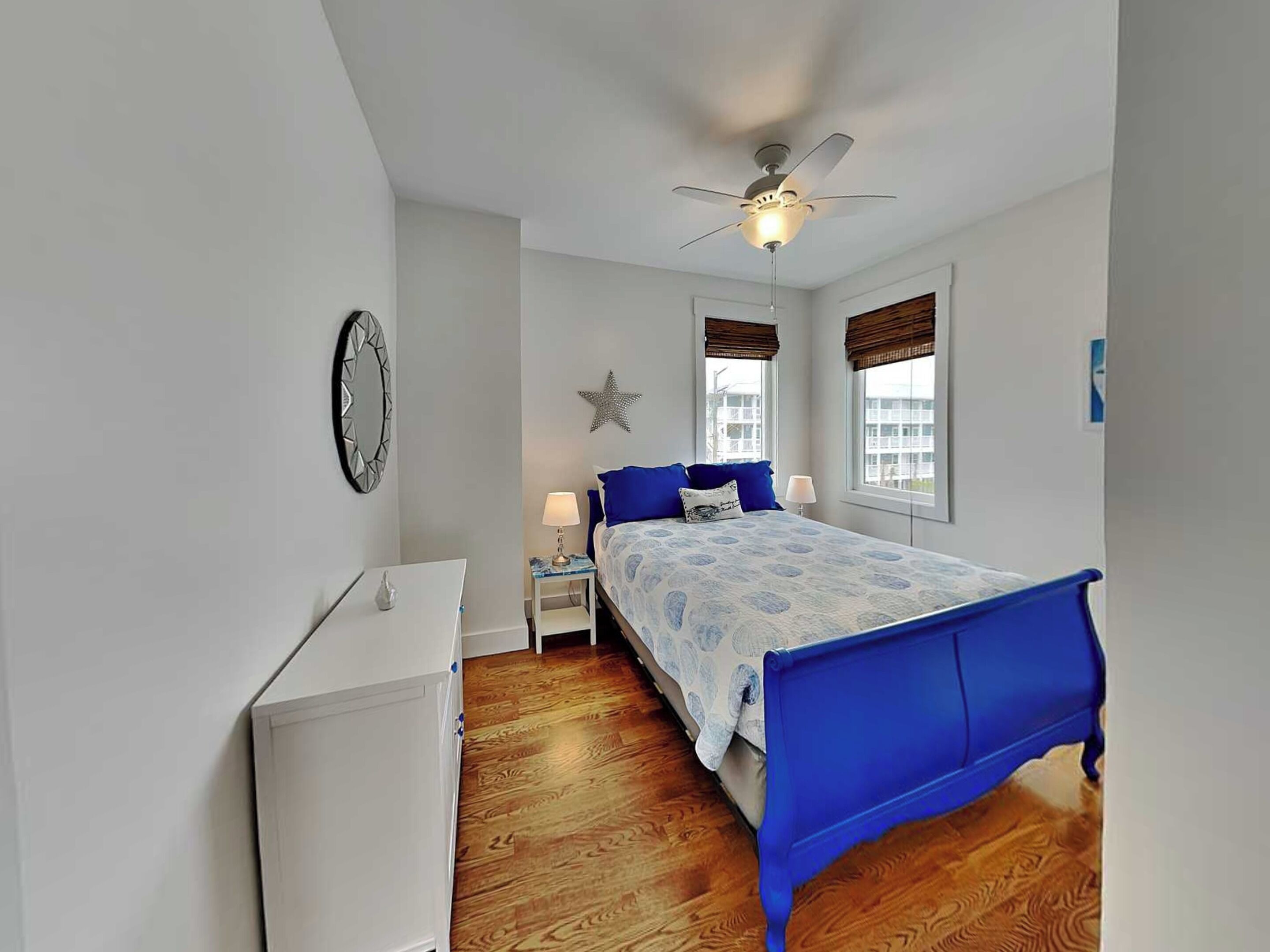 Une chambre à coucher comprenant un lit, des tables de chevet, un ventilateur de plafond, une décoration en forme d’étoile et une fenêtre avec vue.