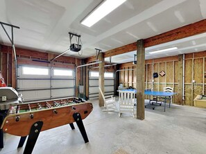 Un'ampia area interna con tavolo da calcio, tavolo da ping pong e un angolo salotto con sedie.