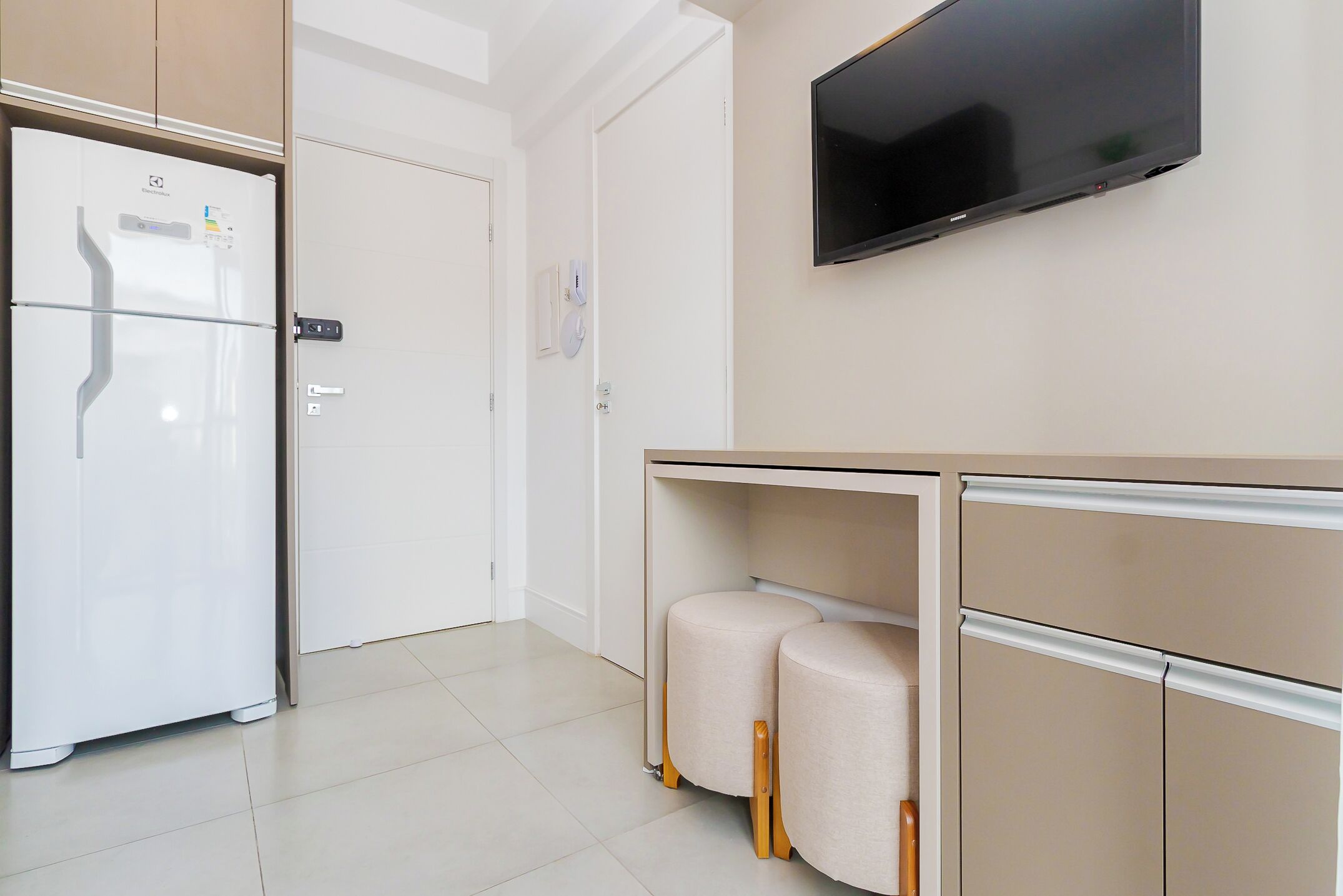 A modern kitchen with a built-in refrigerator, a wall-mounted TV, and a wooden countertop.