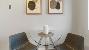 A room with a glass table, two framed abstract paintings, and a white vase on the table. - Salem 2B rep (Arlington Heights)