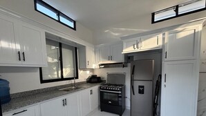 Una cocina moderna con armarios blancos, un refrigerador de acero inoxidable, una estufa a gas y un microondas.