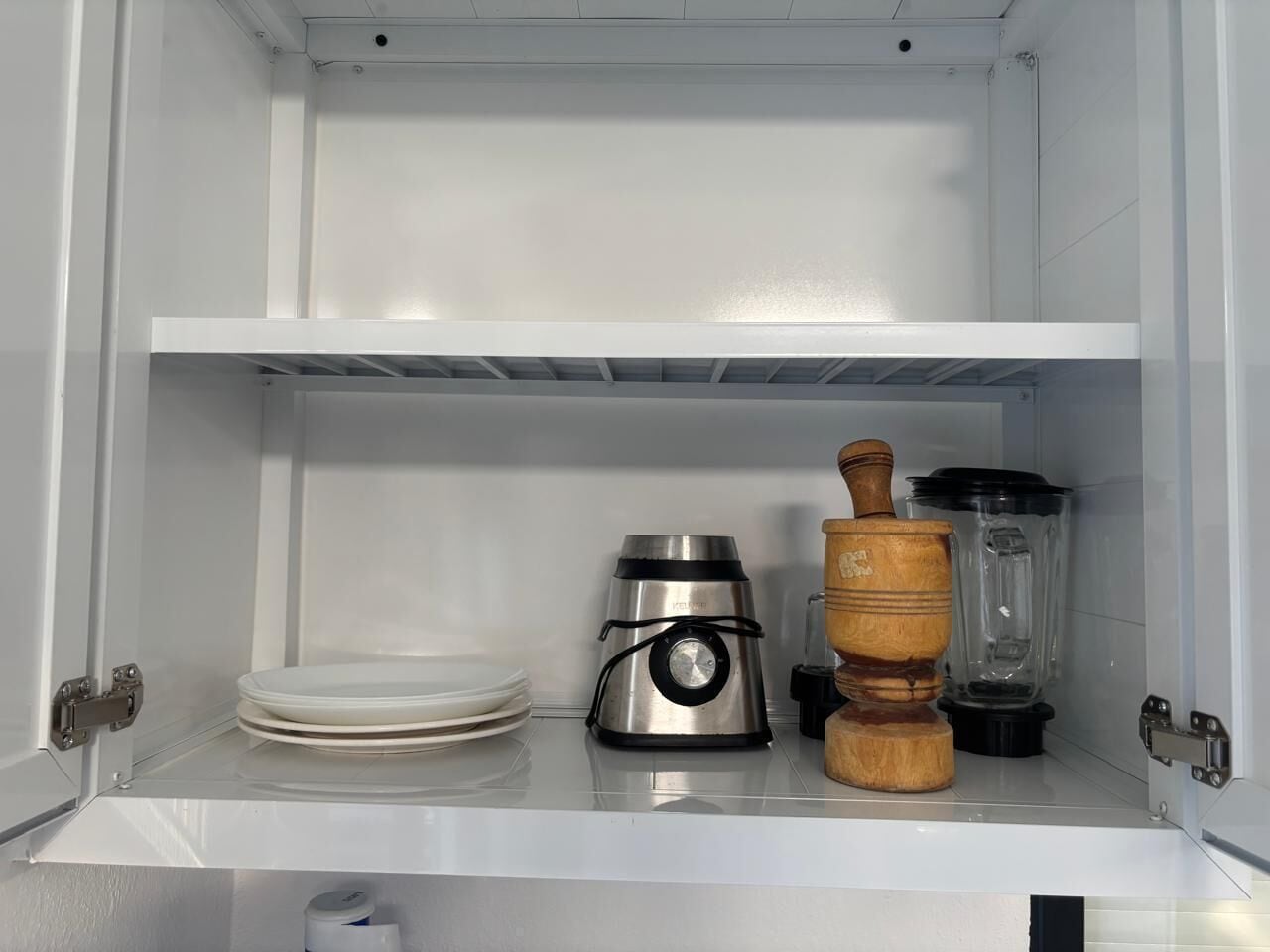 A kitchen with a stainless steel coffee maker, a wooden rolling pin, and a blender on the counter.