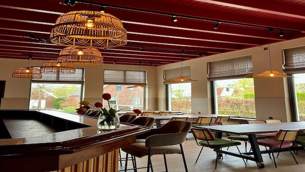A restaurant interior with a high ceiling, exposed beams, and large windows. - Luxury Group Retreat in Nature (Scherpenzeel)