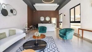 A modern hotel lobby with a reception desk, a white sofa, teal chairs, and a geometric patterned rug. - Relaxing Ocean View Condo (Santo Domingo)
