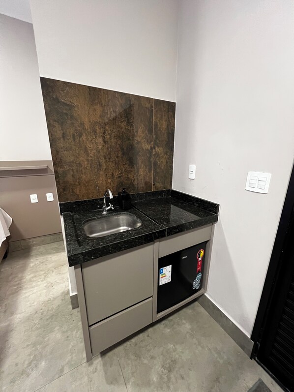 A compact kitchen with a granite countertop, stainless steel sink, and a built-in dishwasher. - Pousada Casa Limão (Rifaina)
