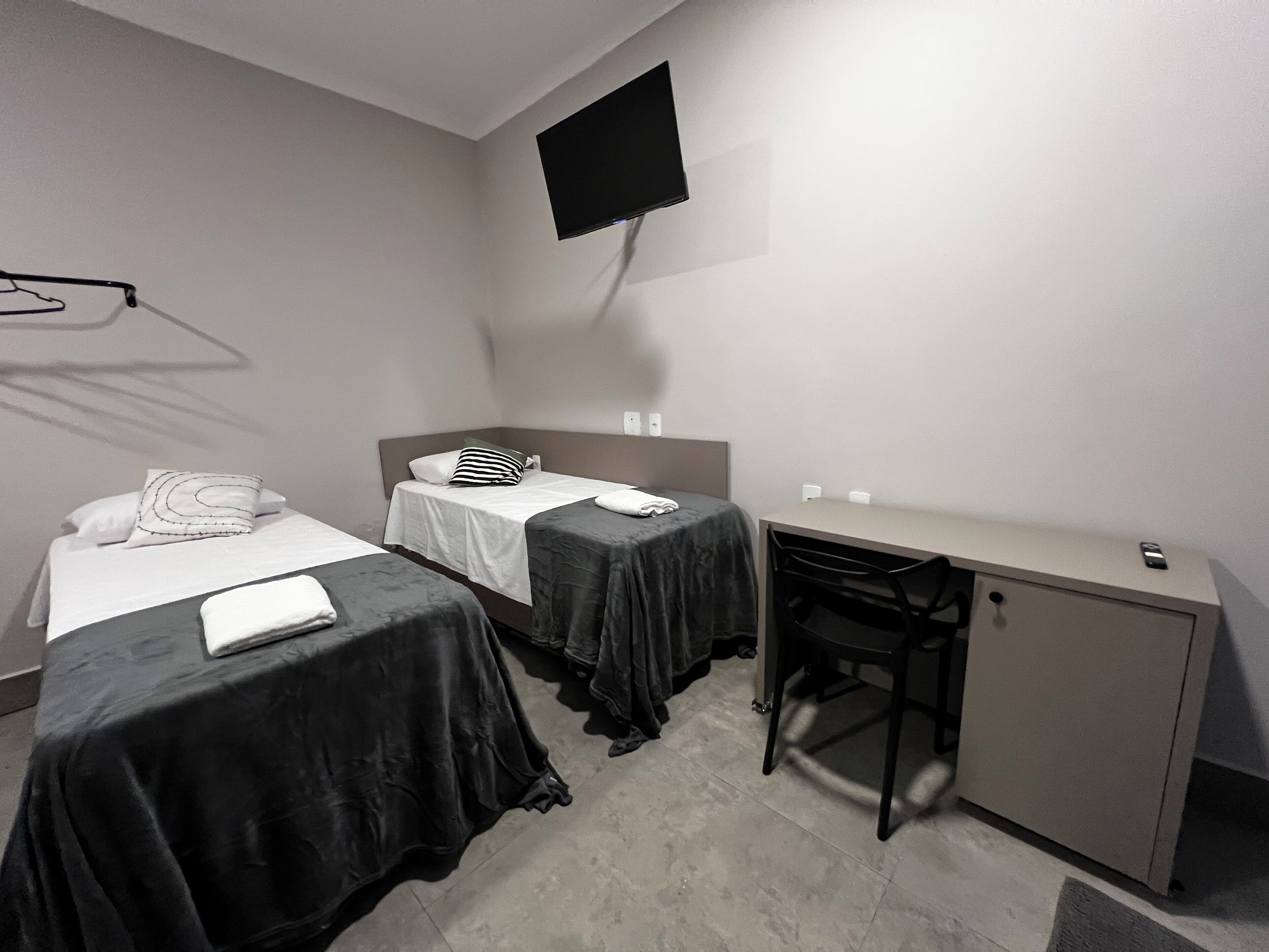 Une chambre d’hôtel avec deux lits, un bureau et une télévision.