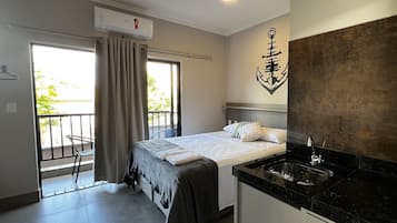 Quarto de hotel com cama, banheiro com pia e varanda.