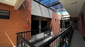 A modern building with a glass roof, brick walls, and a metal railing. - Pousada Casa Limão (Rifaina)