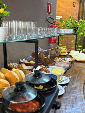 A buffet table with various food items, including bread, pastries, and a selection of cheeses. - Pousada Casa Limão (Rifaina)