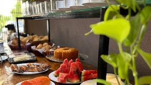 A buffet table with various food items and utensils. - Pousada Casa Limão (Rifaina)