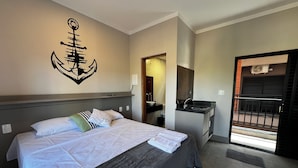 A hotel room with a bed, a small kitchenette, a bathroom, and a balcony. - Pousada Casa Limão (Rifaina)