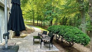 Uma área de pátio com caminho de pedra, mobiliário de exterior e um pequeno jardim.