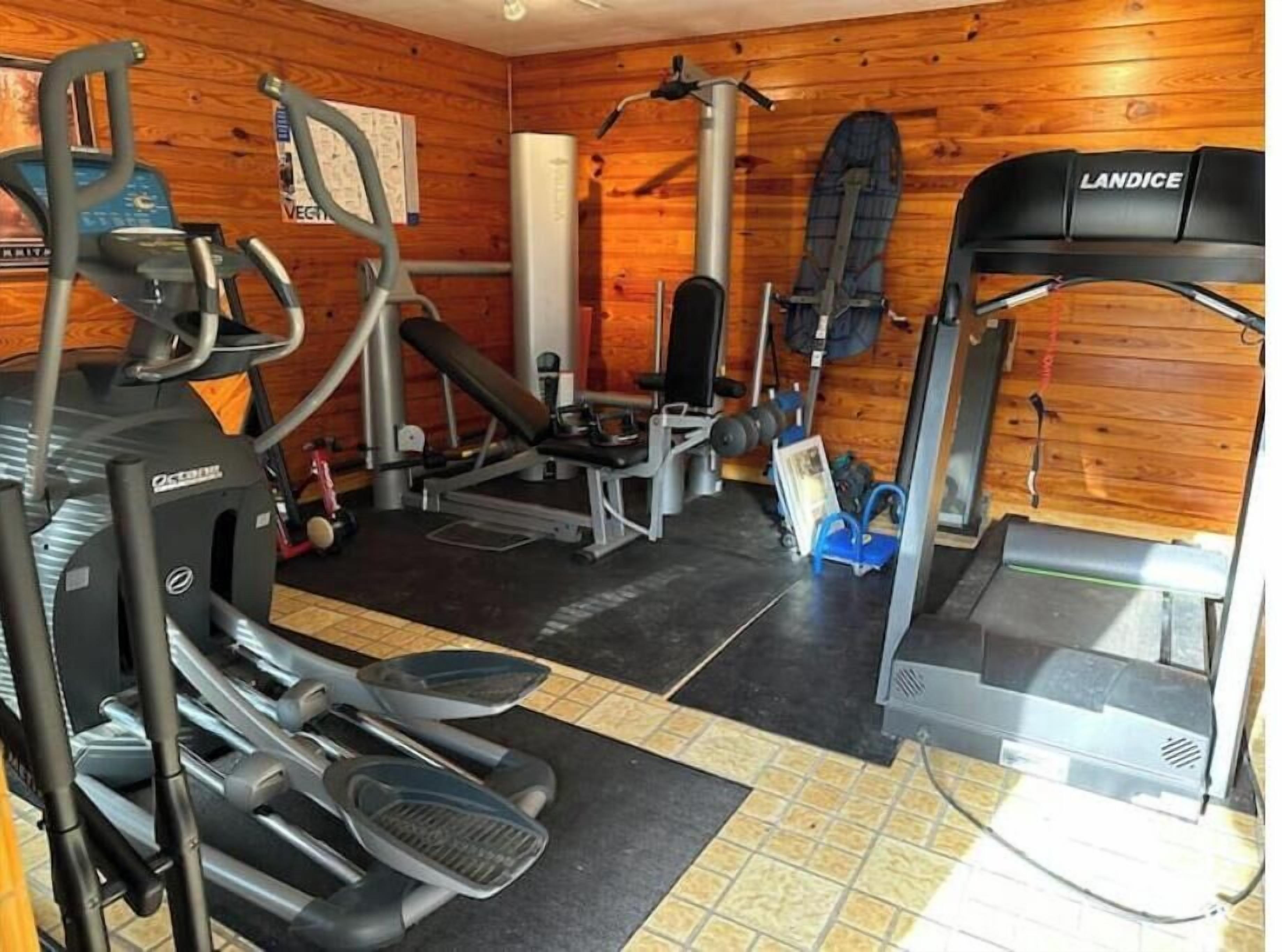 Une salle de sport équipée de divers appareils d’exercice, notamment des tapis de course, un vélo d’appartement et des appareils de musculation.