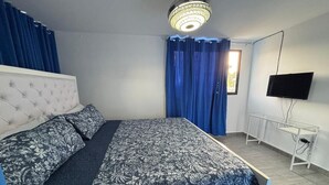 A bedroom with a bed, curtains, a television, and a desk.