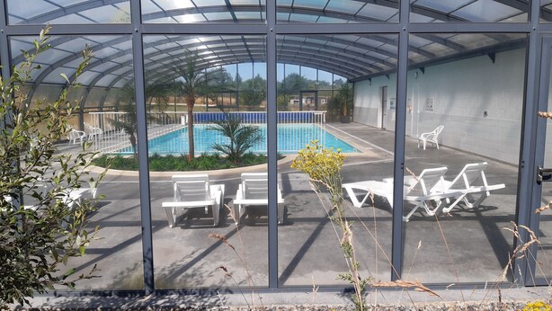 A covered outdoor swimming pool with lounge chairs and a palm tree. - Calm and nature 40kms from Mt St Michel Chausey near Granville and beaches (Longueville)