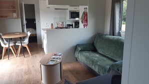 A compact living space with a kitchenette, a dining area, and a sofa. - Calm and nature 40kms from Mt St Michel Chausey near Granville and beaches (Longueville)