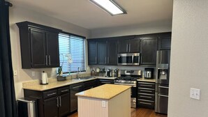 Uma cozinha moderna com armários escuros, eletrodomésticos de aço inoxidável e uma ilha central.