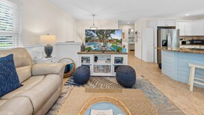 A modern living room with a beige sofa, a coffee table, and a TV displaying a scenic view.
