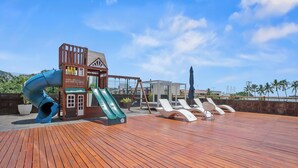 A wooden deck with a play area including a slide, lounge chairs, and a small building with a sign. - 3rd-Floor Gem w/ Cruise Views & Rooftop Lounge (Puerto Vallarta)