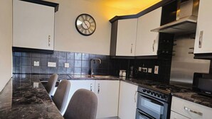 Una cocina moderna con una paleta de colores blanco y negro, horno empotrado y un reloj en la pared.