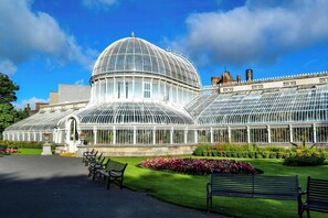 A large greenhouse with a domed roof, surrounded by well-maintained gardens and benches.