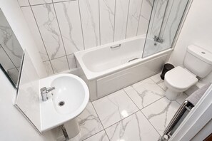 A modern bathroom with a bathtub, toilet, and sink.