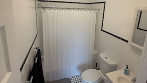 A bathroom with a white toilet, a sink, and a shower curtain. - Pet Friendly Apartment In Arena District with Parking (Detroit)