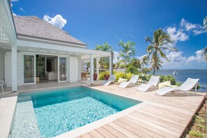 A poolside area with a view of the ocean, lounge chairs, and a covered patio. - Luxury villa Petit Pinsonnelle - Swimming pool & Lagoon access - Cap-Est, Martinique (Le François)