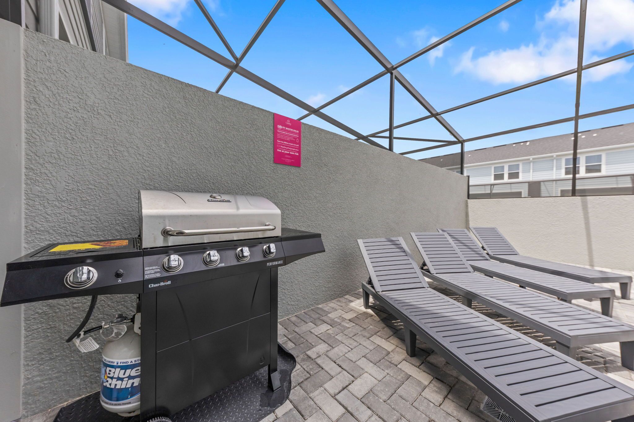 Eine Terrasss mit einem Char-Broil Grill, Liegestühlen und einer Dose Blue Rhino Bier.
