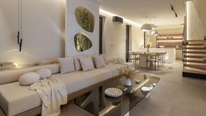 A modern living room with a sofa, a glass coffee table, and a dining area with a kitchen in the background. - Pet friendly home in Petrcane with sauna (Petrcane)