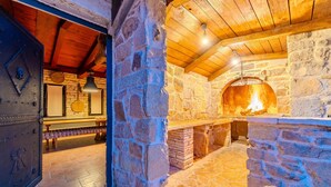A stone-walled room with a wood-burning oven, a rustic wooden door, and a bench. - Amazing home in Zagrad (Zagrad)
