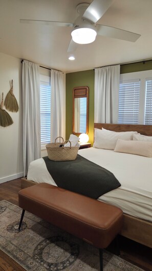 A bedroom with a bed, bedside lamp, bedside table, and a ceiling fan.