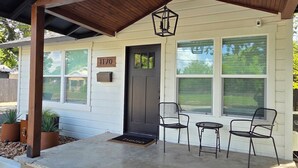 A covered porch with a wooden roof, a black door, and a number '1170' sign.