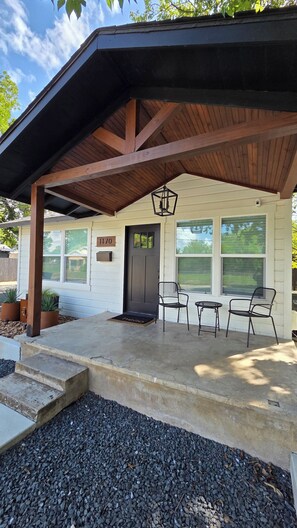 A covered porch with a wooden roof, a black door, and a number '1170' sign.