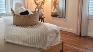 A bedroom with a wooden bed, a bedside lamp, a mirror, and a wicker basket on the bed.