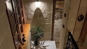 Un escalier avec une rampe en bois, un pot de fleurs à sa base et un mur à la surface texturée.