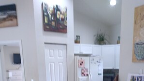 Ein Essbereich mit einem Holztisch und Stühlen, eine Küche im Hintergrund und ein Gemälde an der Wand.