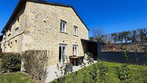 A stone building with a two-story structure, a front door, and a small outdoor seating area.