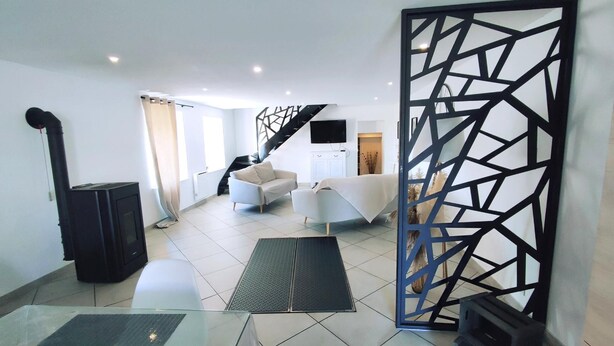 A modern living room with a sofa, a coffee table, a TV, and a staircase. - HEIDI - SURY - Gîte (SURY)