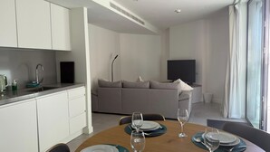 Eine moderne Küche mit weißen Schränken, einer Spüle aus Edelstahl und einem Essbereich mit einem Holztisch, gedeckt für vier Personen.
