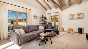 Ein geräumiges Wohnzimmer mit grauem Sofa, einem runden Couchtisch und einem Bücherregal.