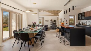 Eine moderne Küche mit einem langen Esstisch, Barhocker und einer großen Kochinsel.