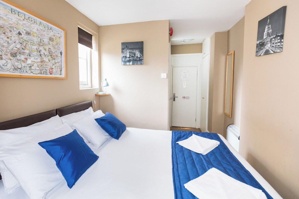 Une chambre d’hôtel avec un grand lit, un lit plus petit, une carte de la Belgique et un tableau représentant un pont.