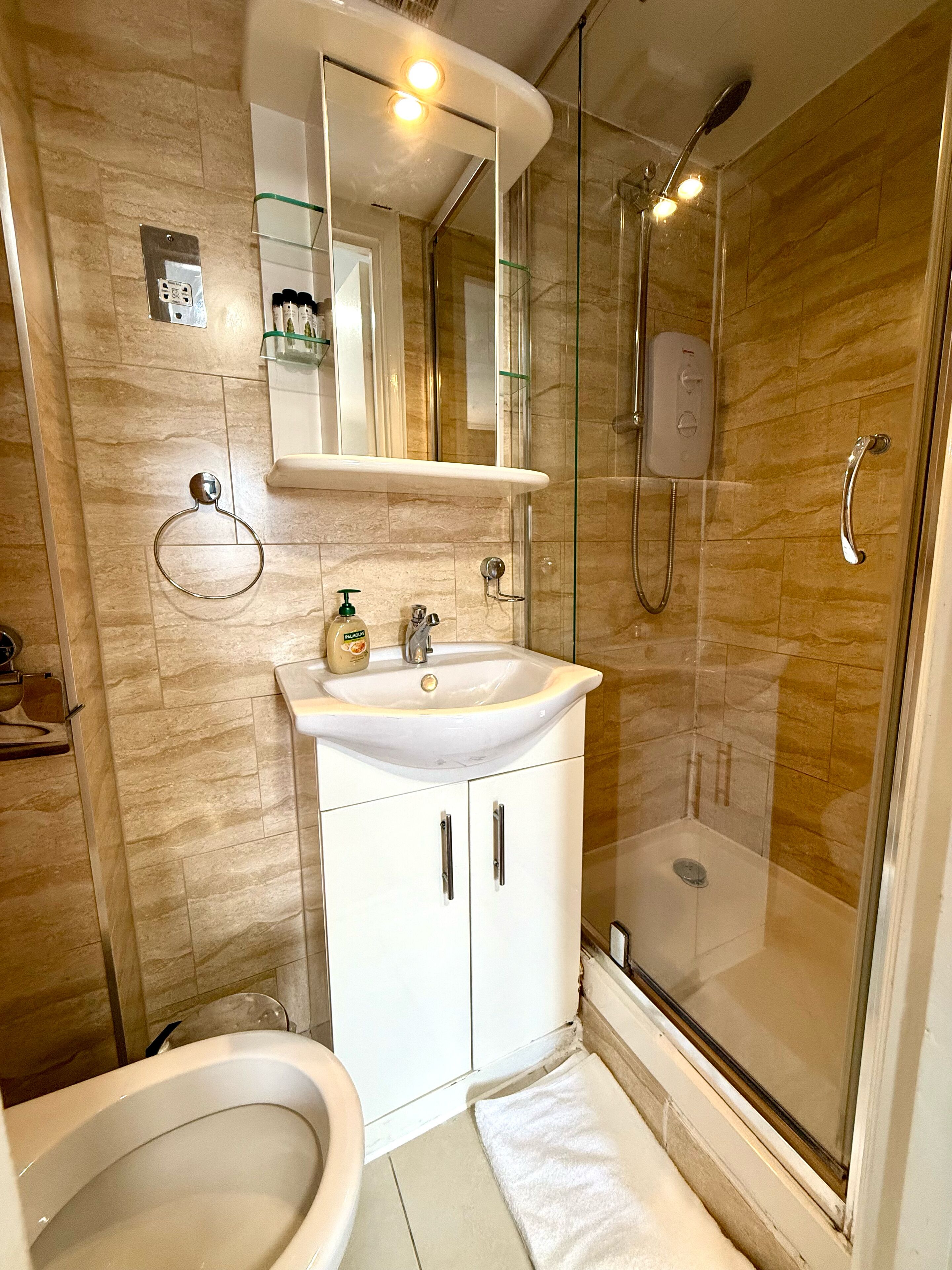 Un baño con lavamanos blanco, espejo y cabina de ducha de vidrio.