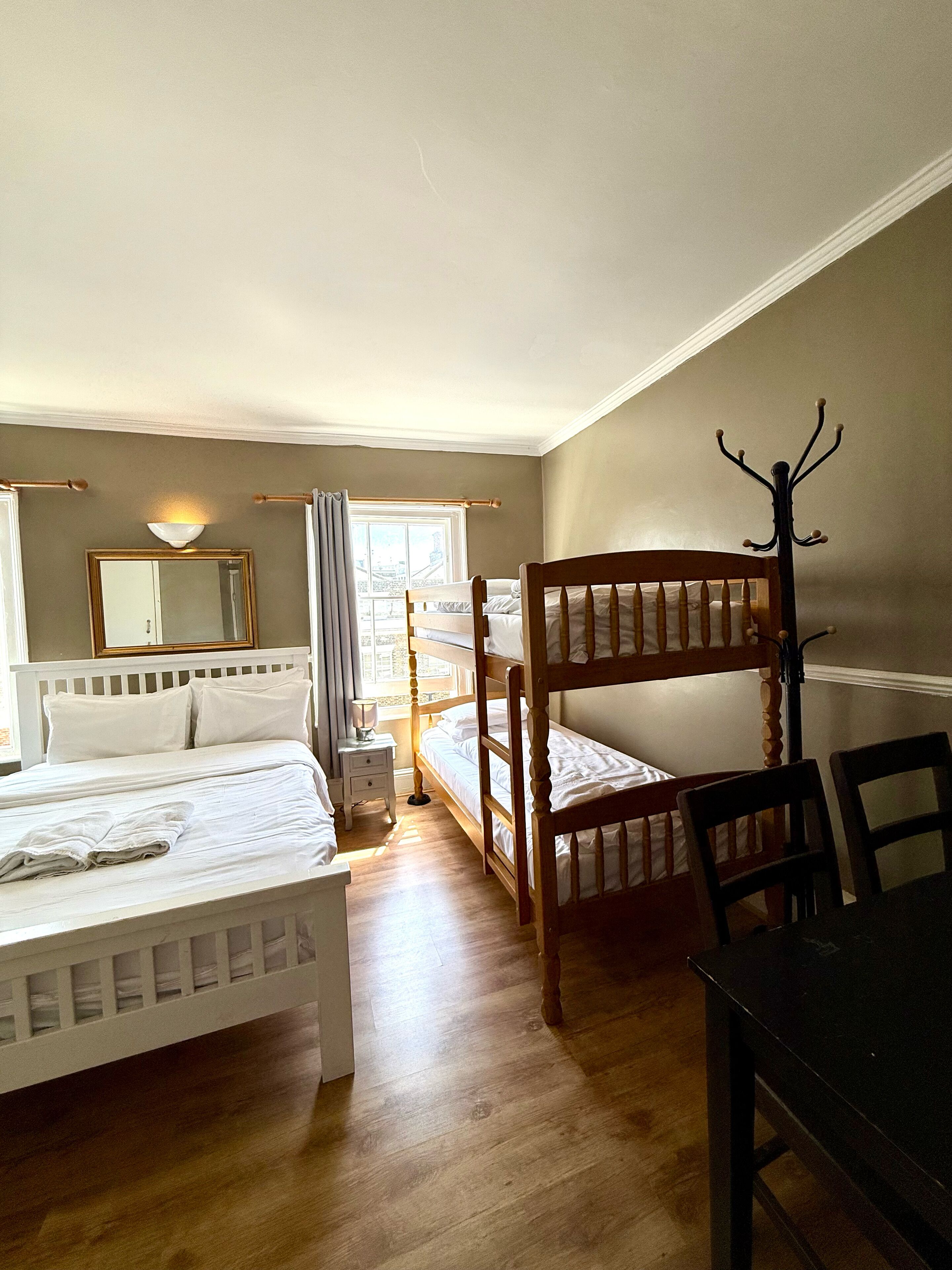 Une chambre avec un lit superposé, un lit simple, une table et une chaise.