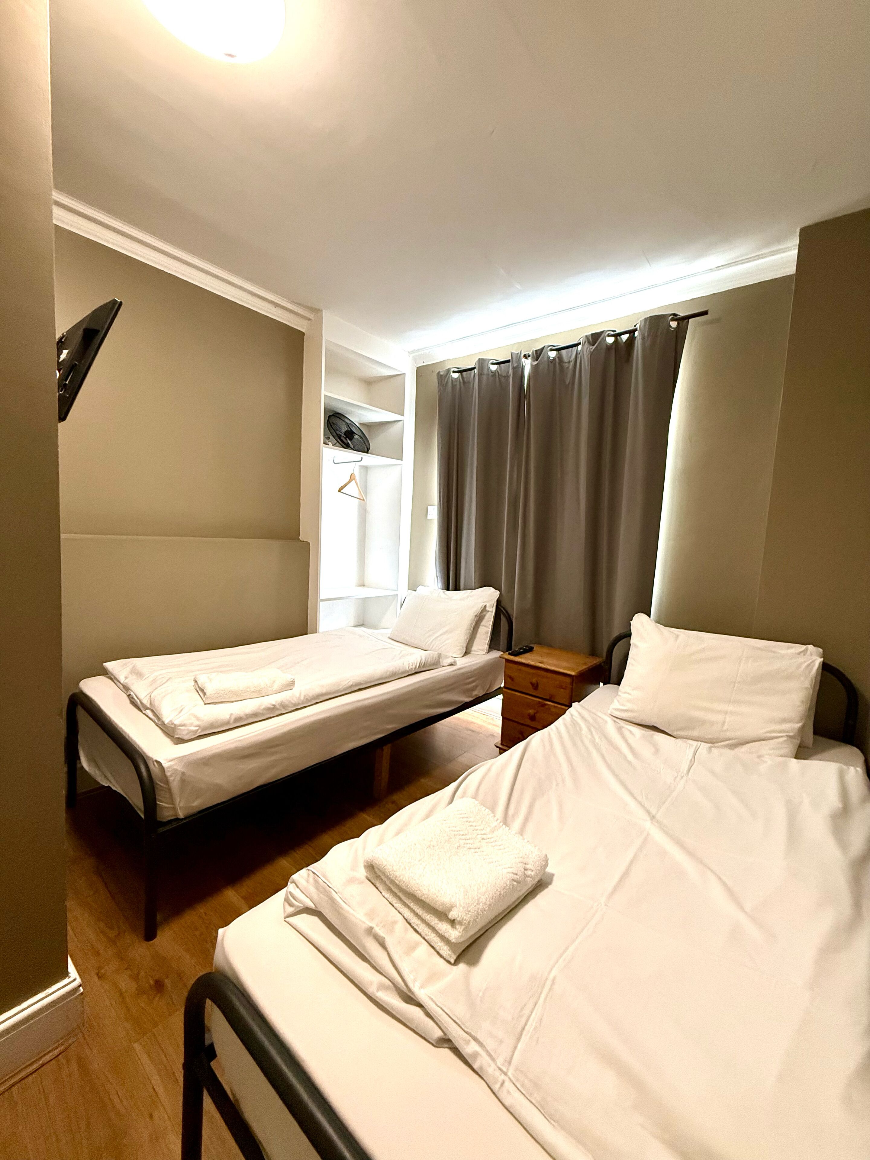 Habitació d'hotel amb dos llits individuals, una nituixi de fusta, una taula petita i una cadira.