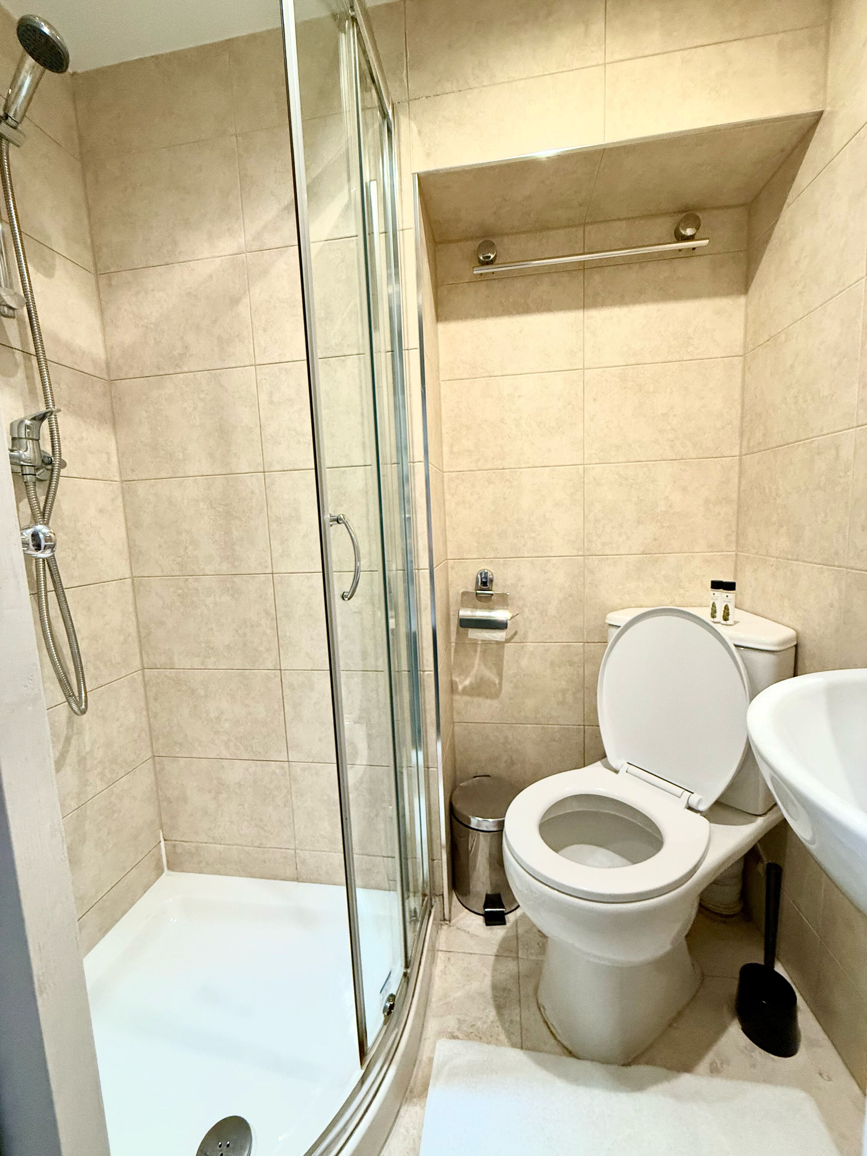A bathroom with a glass-enclosed shower, a toilet, and a sink.