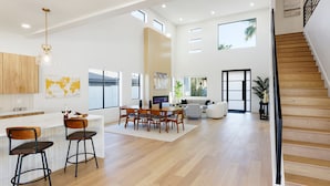 Un vaste espace de vie agrémenté d’un escalier en bois, un coin repas avec une grande table et des chaises, et une cuisine dotée de meubles en bois et d’une carte du monde accrochée au mur.