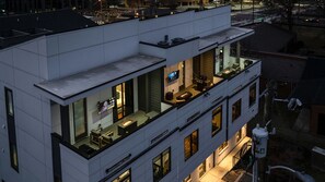 A modern building with a rooftop bar featuring outdoor seating and a TV screen. - Broadway Getaway-rooftop Patio-mins to The Gulch (Nashville)